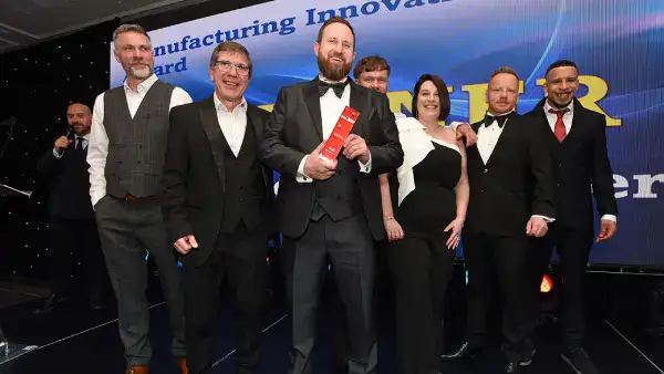 S Jones Containers team on stage at the Made in the Midlands Awards 2025, holding the Manufacturing Innovation Award trophy after being announced as winners.