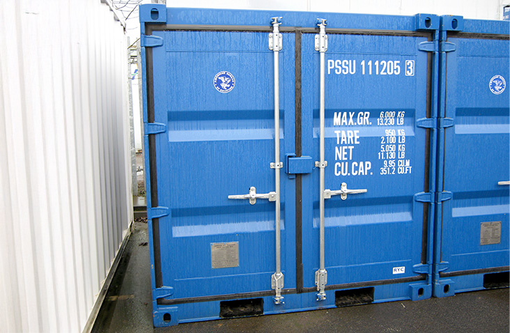 Blue 8ft shipping container with lockable double doors, factory markings, and identification number