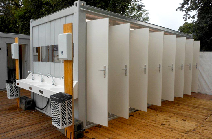 Modular toilet unit with multiple private stalls and wash basins for staff welfare and event facilities.
