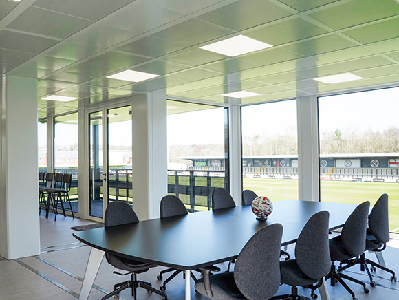 Modern modular office building interior with meeting room, large windows, and flexible workspace overlooking sports grounds.