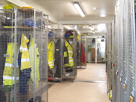 Modular welfare unit interior with mesh lockers for PPE and workwear storage, providing secure staff changing and welfare facilities on construction sites.