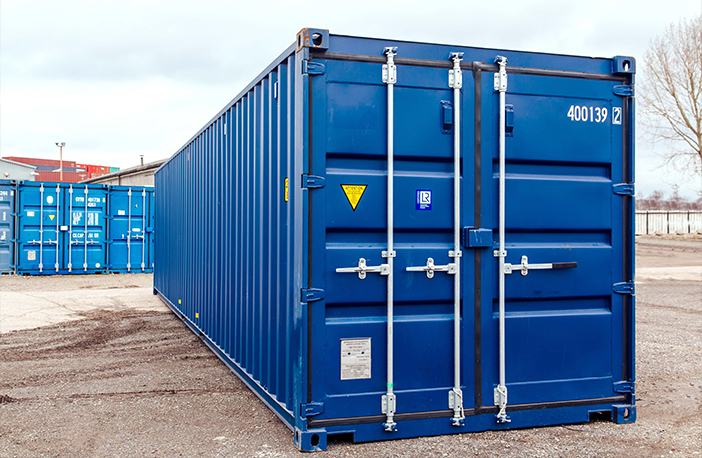Front of a blue 30ft container with closed double doors, locking bars and safety decals, photographed on a depot yard