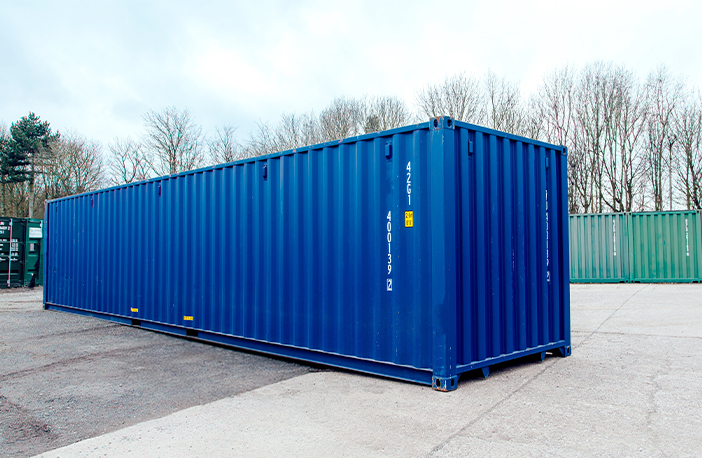 Side profile of a blue 30ft container on hardstanding, long corrugated wall with lifting points and identification marks