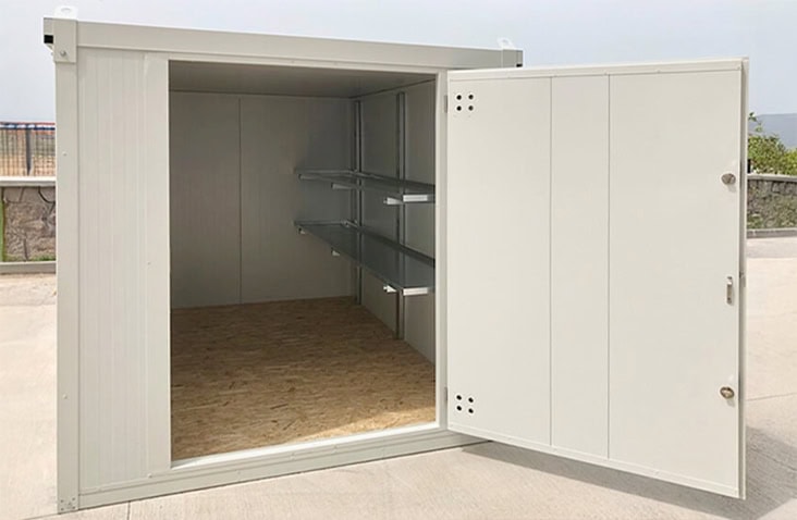 White insulated flat pack storage unit with open double doors, showing a plywood floor and fitted metal shelving along the interior wall, designed for secure and temperature-controlled storage of goods.