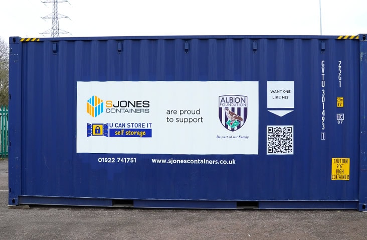 Blue 20ft shipping container with large S Jones Containers, U Can Store It, and Albion Foundation partnership branding displayed across the side panel.