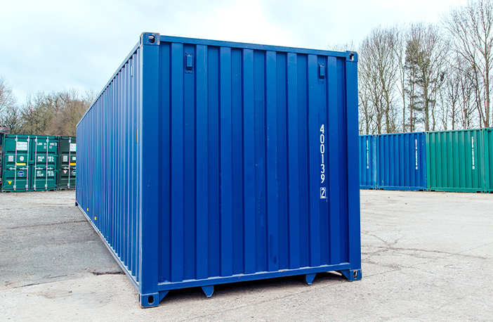 Blue 30ft shipping container in a yard, corrugated steel sides and corner castings visible