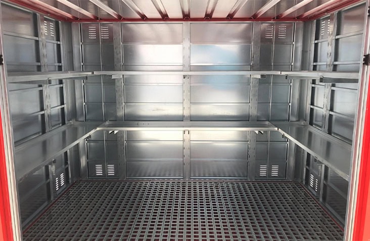     Interior of a red flat pack chemical storage unit showing metal shelving on both sides, ventilation panels in the walls, and a bunded steel floor for safe COSHH-compliant hazardous liquid storage. 