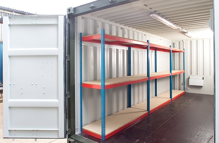 Interior of a shipping container fitted with self-assembly boltless shelving units along one wall for organised storage. 