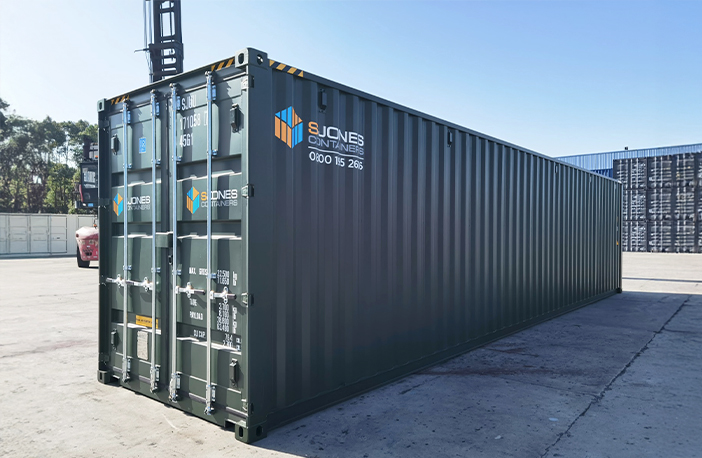 Green 40ft high cube shipping container, providing extra internal height for storage or export use, pictured on an industrial container depot.