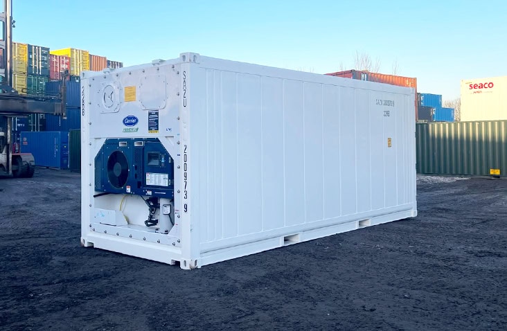 Rear-side perspective of a 20ft white refrigerated shipping container, showing the refrigeration unit at one end and smooth insulated exterior panels, positioned outdoors in a container storage yard. 