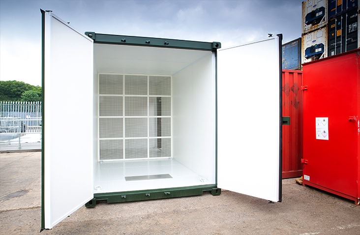 Open green shipping container fitted with a white mesh bulkhead partition and steel frame, designed for specialist plant room or equipment storage, with double cargo doors wide open. 