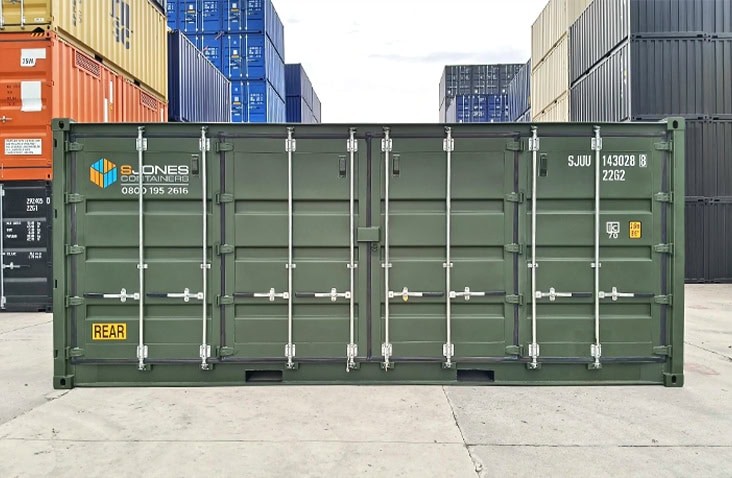 Front view of a green 20ft side opening shipping container with side doors closed, featuring S Jones Containers branding and yellow “REAR” marking, positioned in a container yard surrounded by stacked units. 