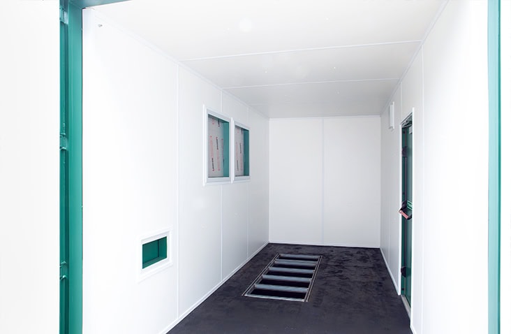 Clean white-lined insulated shipping container interior with built-in floor drainage and ventilation panels. 