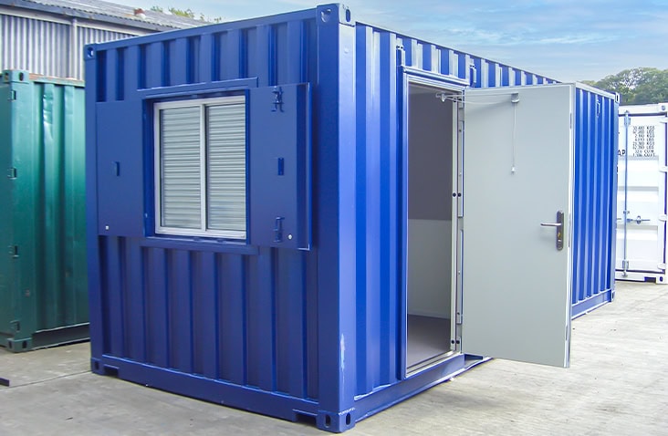 Blue 20ft converted office container with open personnel door and shuttered window, shown on an outdoor hardstanding surface. 