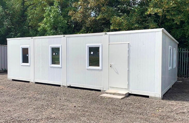 Linked flat pack office units installed together to create a larger modular workspace with multiple windows and a single door.
