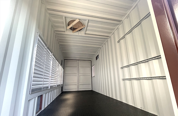 Interior of a containerised boiler housing, featuring louvred ventilation panels, a non-slip steel floor, wall mounting rails, and a ceiling aperture for equipment connections.