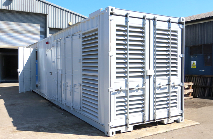 Containerised compressor housing unit with full-height louvred ventilation panels on the doors and sides, positioned outdoors on an industrial site.