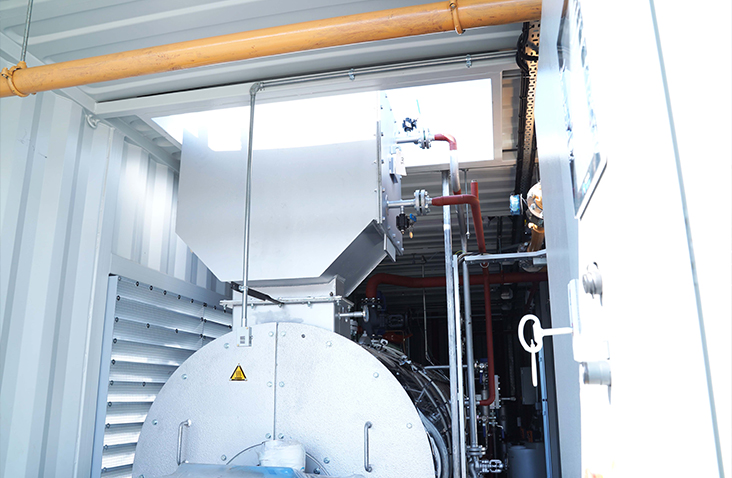 View inside a containerised plant room showing boiler-housed equipment, pipework and ventilation.