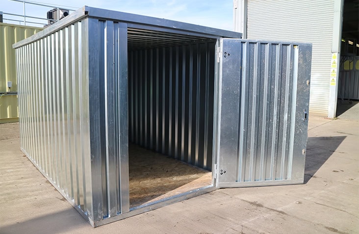 Galvanised 2m x 3m flat pack storage unit with the single door open, showing internal space and timber floor. 