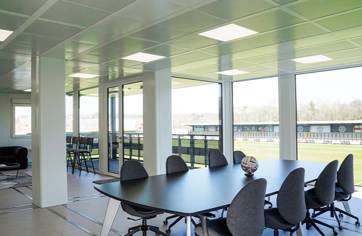 Modular boardroom with a conference table and floor-to-ceiling windows offering views of the football ground.