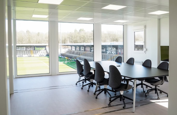 Spacious modular meeting room with a large conference table and panoramic views of a football pitch.