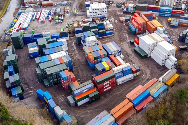 Aerial drone view of a busy container depot located in Aldridge and operated by S Jones Containers.  Stacks of multicoloured shipping containers arranged across a large industrial yard.