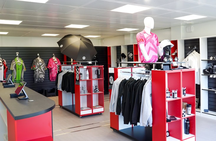 Interior of a modular retail unit fitted with shelving, display racks, mannequins and merchandise, used as a club shop or store space. 