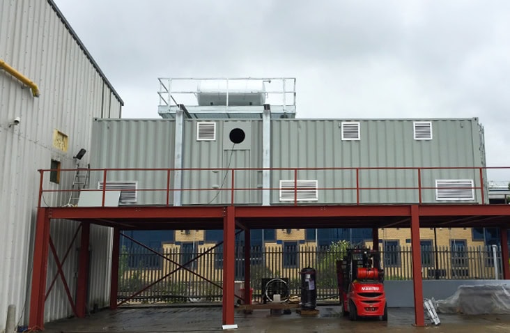 40ft high cube container units installed to house a steam boiler, showing large containerised boiler housings mounted on a raised steel platform with ventilation systems, access points and safety infrastructure. 