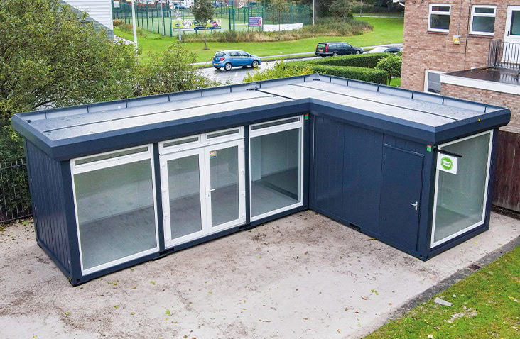 Two modular bays forming a connected modular building, showing an L-shaped modular structure with glazed doors, flat roof, and secure external access, suitable for healthcare, education or community use.