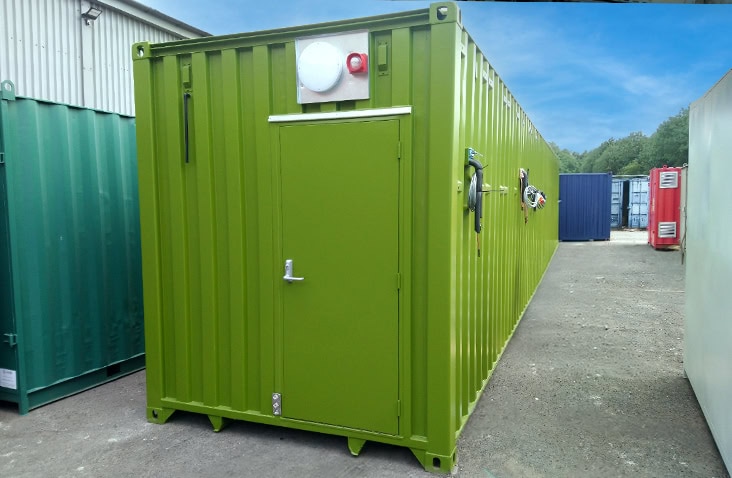 40ft green shipping container converted for switchgear or plant equipment, featuring a personnel access door, external alarm beacon, ventilation fittings and lockable handles for industrial plant housing.