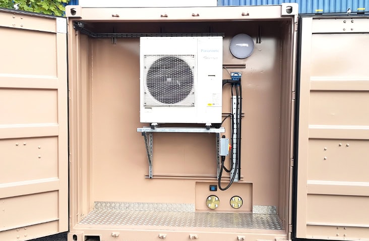 Open 20ft shipping container showing installed HVAC unit, with wall-mounted air conditioning equipment, electrical connections and chequer plate flooring inside a bespoke container conversion.