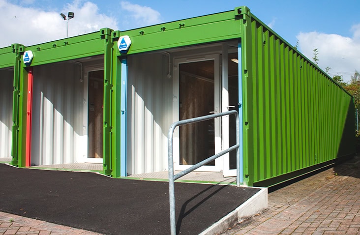Container-based retail and workspace units with double glazed entrance doors, showing green shipping containers converted into secure commercial units.