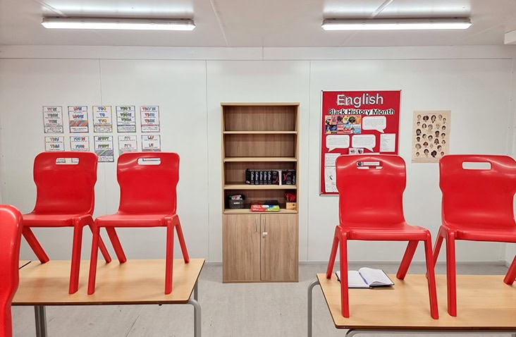Modular school learning space with classroom furniture and wall displays, showing desks, chairs, storage units and educational posters inside a fully fitted modular education unit. 