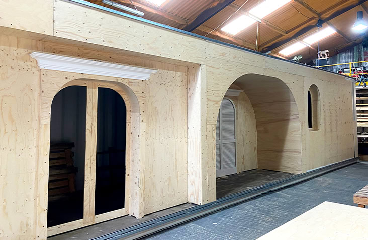 Interior workshop view showing bespoke timber cladding and arched openings being constructed inside a shipping container, part of the custom container conversion for The House of Peroni venue.