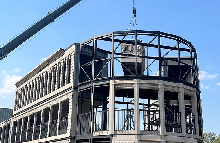 Steel framework installation on a containerised Flatiron building, with curved structural elements being lifted into place as part of a bespoke multi-storey container conversion.