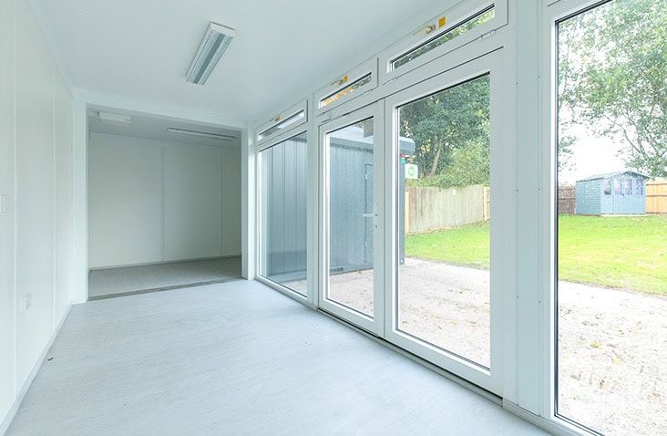 Health and wellbeing modular building interior, showing a spacious, light-filled room with floor-to-ceiling windows, hygienic finishes and flexible layout suitable for a health sanctuary or therapy space.
