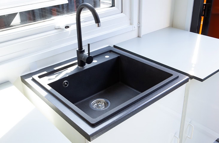 Close-up of laboratory sink and worktop inside a shipping container, showing integrated black sink, tap and durable work surface designed for container-based laboratory environments. 