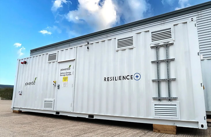 White containerised battery energy storage system with ventilation louvres, access door and safety signage, branded for Powerstar and Resilience+, installed on an outdoor industrial site for grid and energy resilience applications.