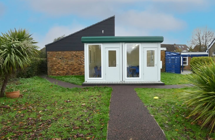 Modular classroom building installed at Carrington Junior School, showing a white bay modular unit with glazed doors and windows positioned within a school playground setting. 