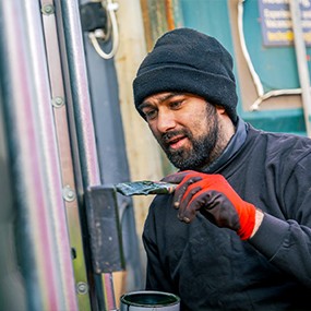 Container repair specialist applying protective coating and maintenance treatment to a shipping container door frame, extending container lifespan and weather resistance.