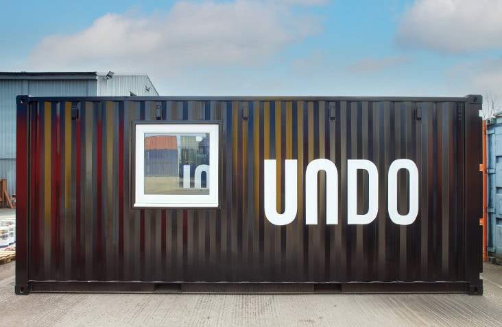 Branded UNDO mobile laboratory converted from a shipping container, showing a black container with external window installation, professional signage and bespoke finish for mobile laboratory use.